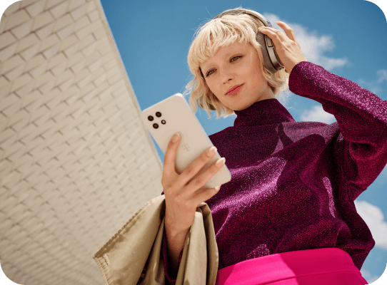 Blonde Frau blickt auf Ihr Smartphone um Gerät für den Ratenkauf auszuwählen